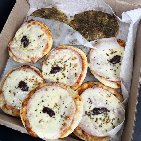 A box of DoughLicious mini Mediterranean pizzas with cheese, olives, and za'atar.