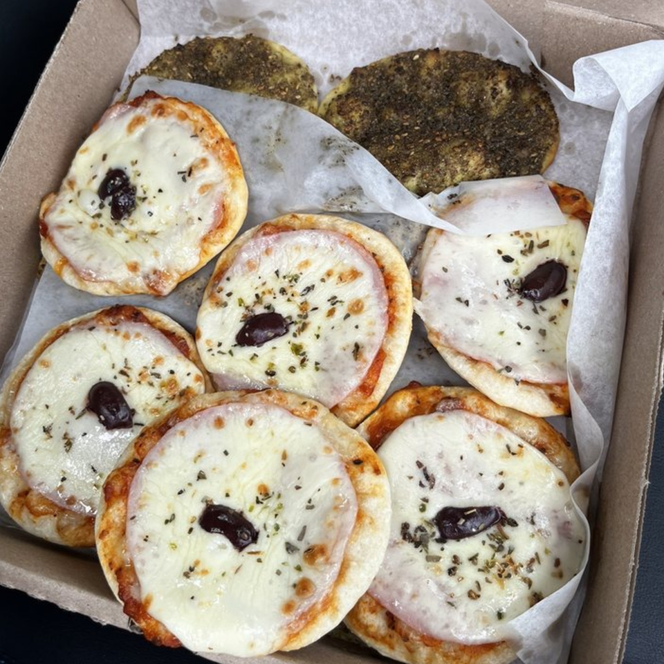 A box of DoughLicious mini Mediterranean pizzas with cheese, olives, and za'atar.