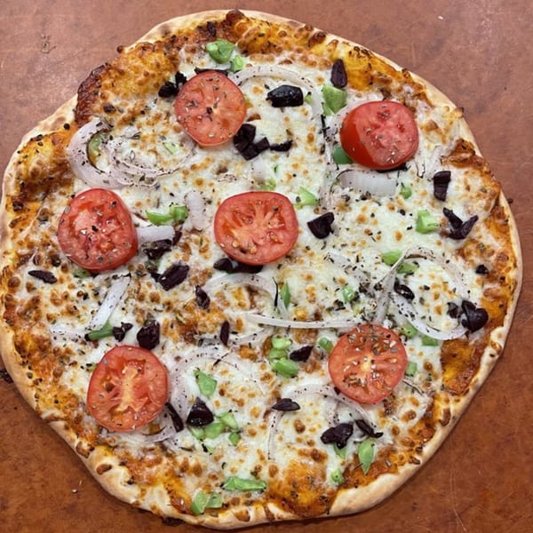 Mediterranean pizza from DoughLicious with tomatoes, onions, olives, and green peppers on a cheesy crust.